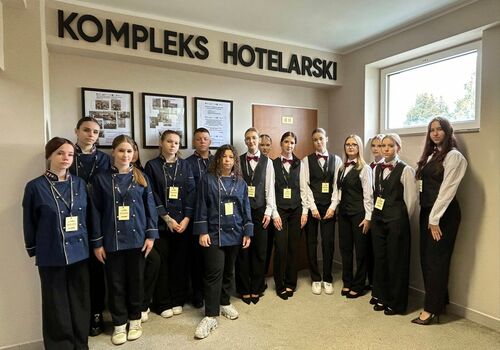 uczniowie stoją w szeregu pod napisem kompleks hotelarski